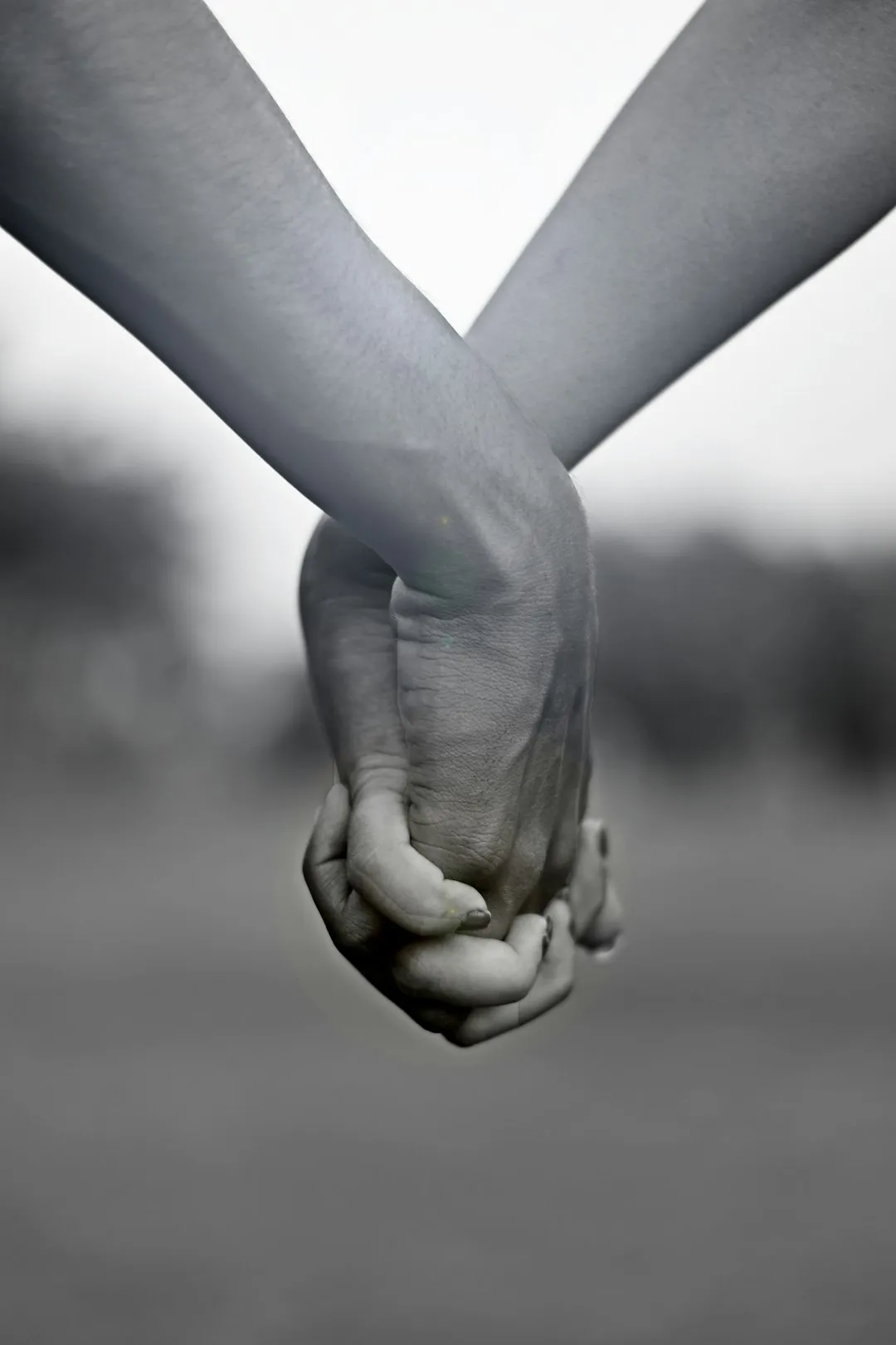 Two people holding hands in a grayscale close-up, a gesture of support and reconciliation