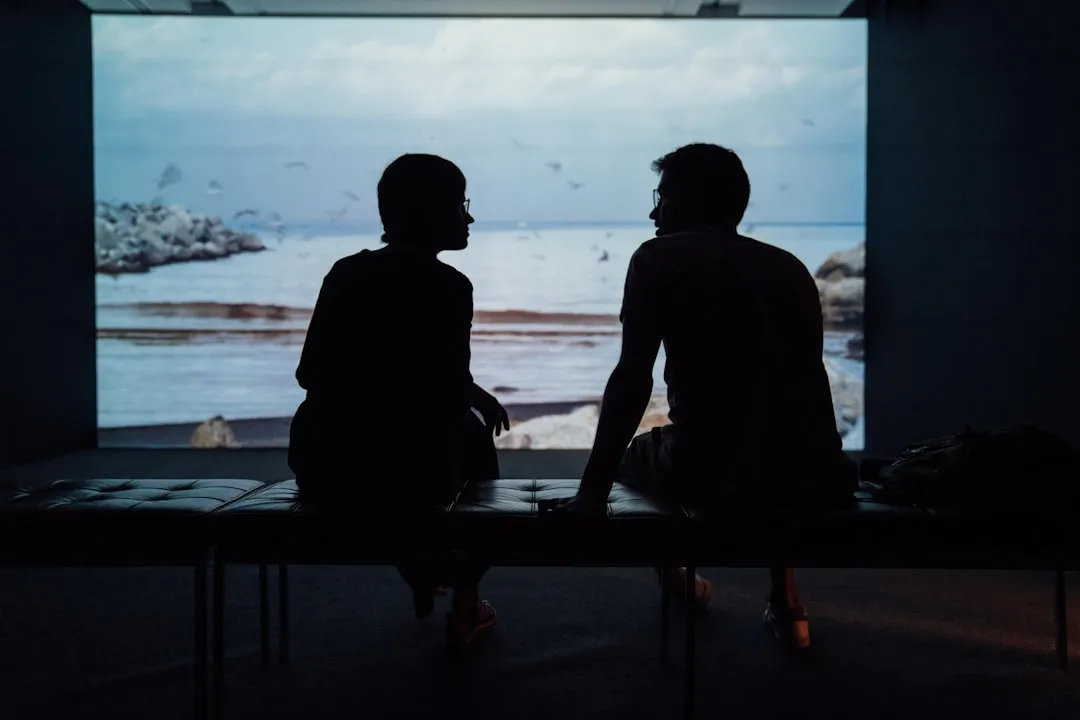 Silhouette of a couple sitting together in conversation, backlit by soft light