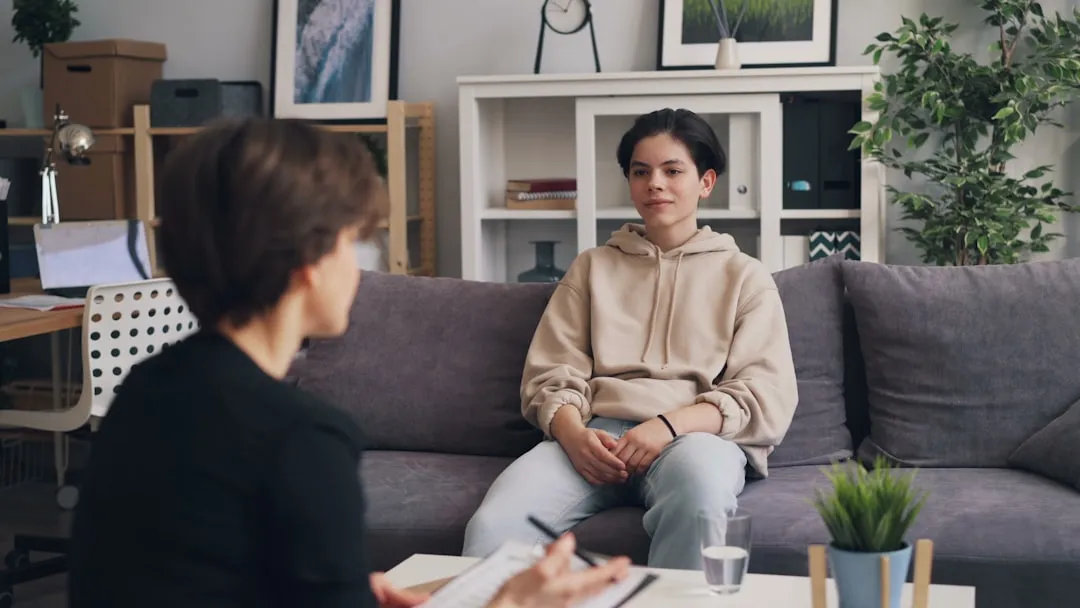 A counselor sitting on a couch in conversation with a young client